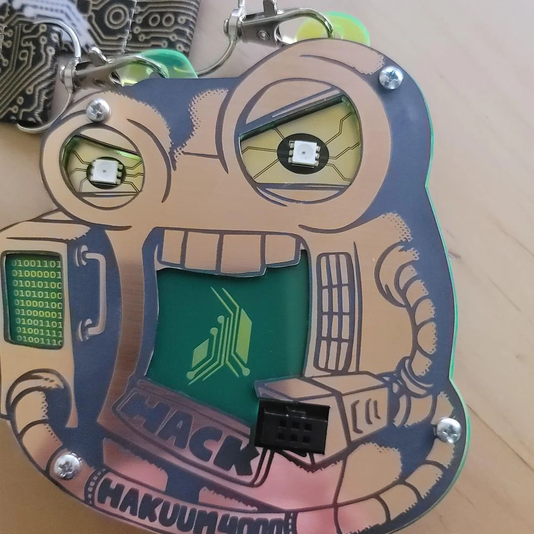 Copper looking face plate badge, maybe a bare circuit board with a black solder mask for the details